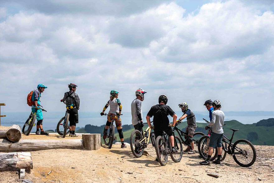Group of mountain bikers resting on a scenic hilltop.