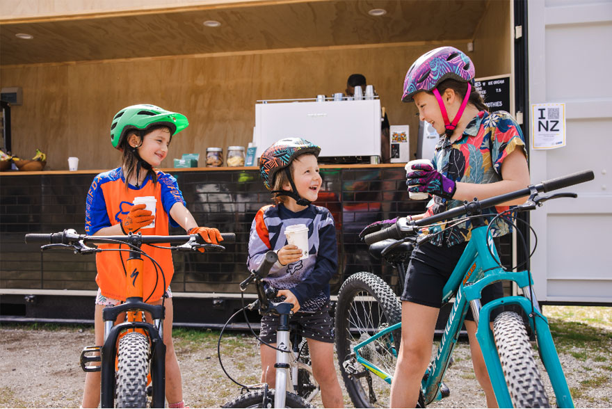 Kids in bike gear enjoying drinks at Te Putake o Tawa car park.